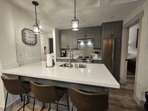 A modern kitchen with a large island, bar stools, stainless steel appliances, and pendant lighting. - Mammoth Lakes Condo-Newly remodeled-Sleeps up to 8 (Mammoth Lakes)