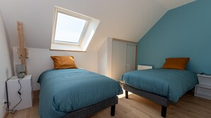 A bedroom with two beds, a skylight, a wardrobe, and a bedside table. - Gîtes Ti Tud-kozh, Location "L' Arguenon" (PLUDUNO)