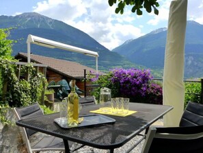 An outdoor dining area with a table and chairs, a bottle of olive oil, and a glass pitcher. - Tschingeli by Interhome (Gampel-Bratsch)