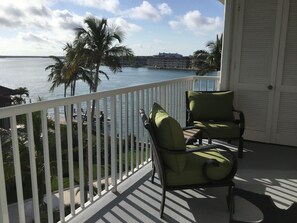 Enjoy breathtaking views of the water from this balcony, featuring two comfortable chairs.