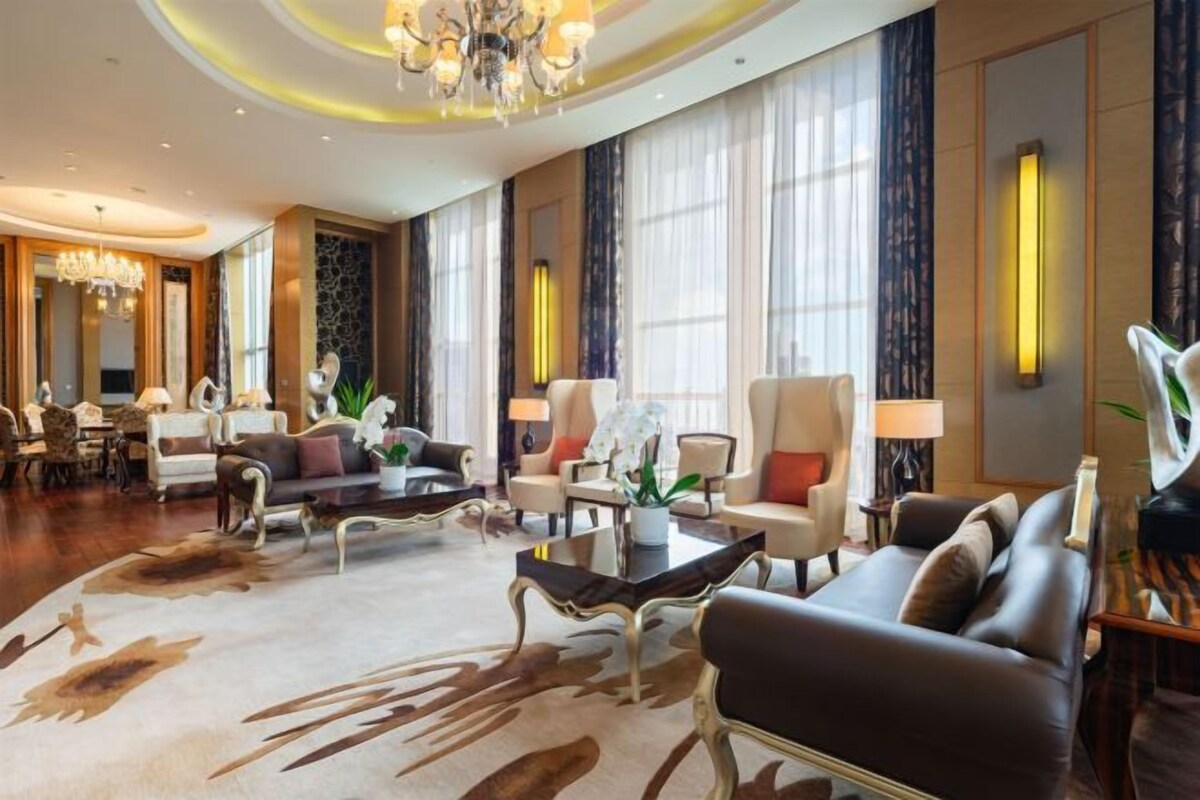 Un salon spacieux avec un grand canapé, des fauteuils, une table basse et un lustre.