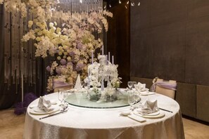 A round table with a glass top, surrounded by white tablecloths, set with plates, glasses, and cutlery. - Howard Johnson Puhui Plaza Chongqing Qijiang (Chongqing)