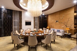 Un comedor formal con una mesa redonda, sillas, una araña y un televisor en la pared.