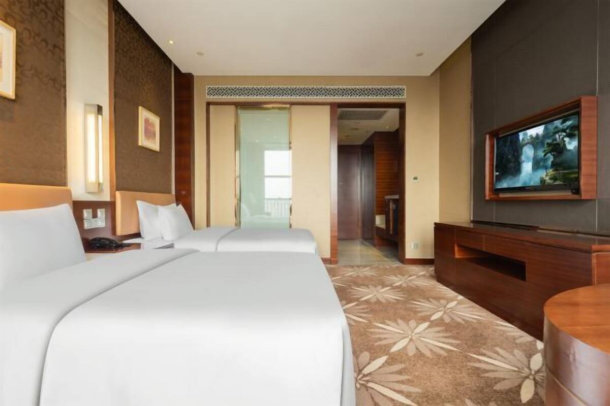 Ein Hotelzimmer mit zwei Betten, einem Fernseher, einem Schreibtisch und Blick ins Freie.