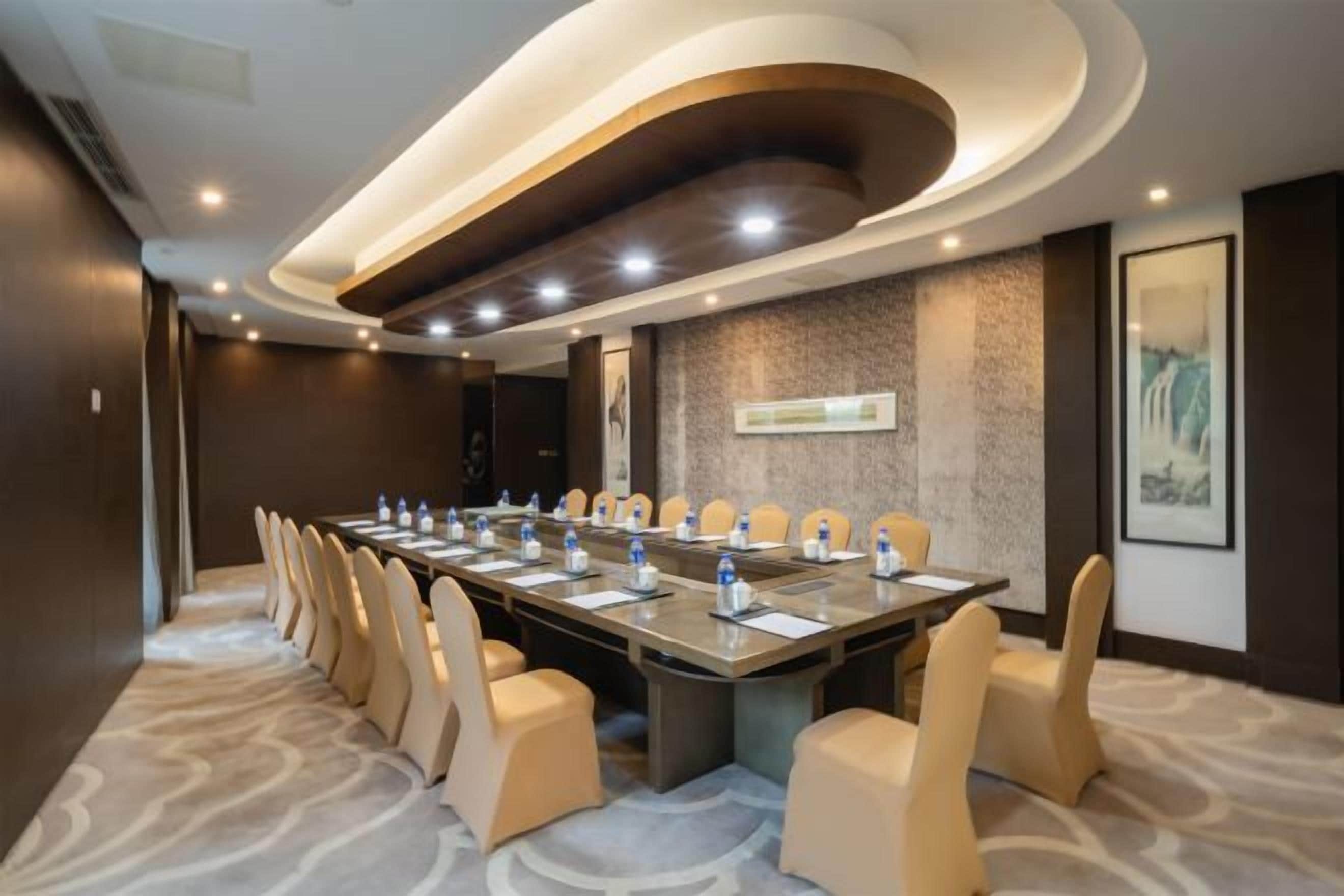 A conference room with a long table, multiple chairs, and a carpeted floor.