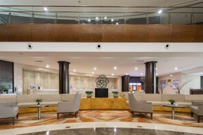 A hotel lobby with a reception desk, seating area, and a glass railing overlooking the space. - Howard Johnson Puhui Plaza Chongqing Qijiang (Chongqing)