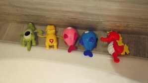 A row of colorful plastic toys on a wooden ledge.