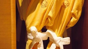 A yellow towel with a duck design and a white towel tied with a bow.