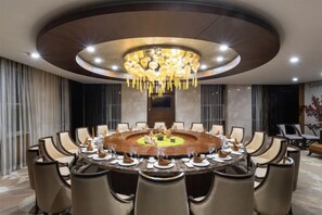 A round dining table with multiple chairs, a chandelier, and a modern interior design.