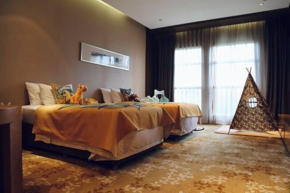 Ein Hotelzimmer mit zwei Betten, einem großen Fenster, einer zeltartigen Konstruktion und einem gerahmten Bild an der Wand.