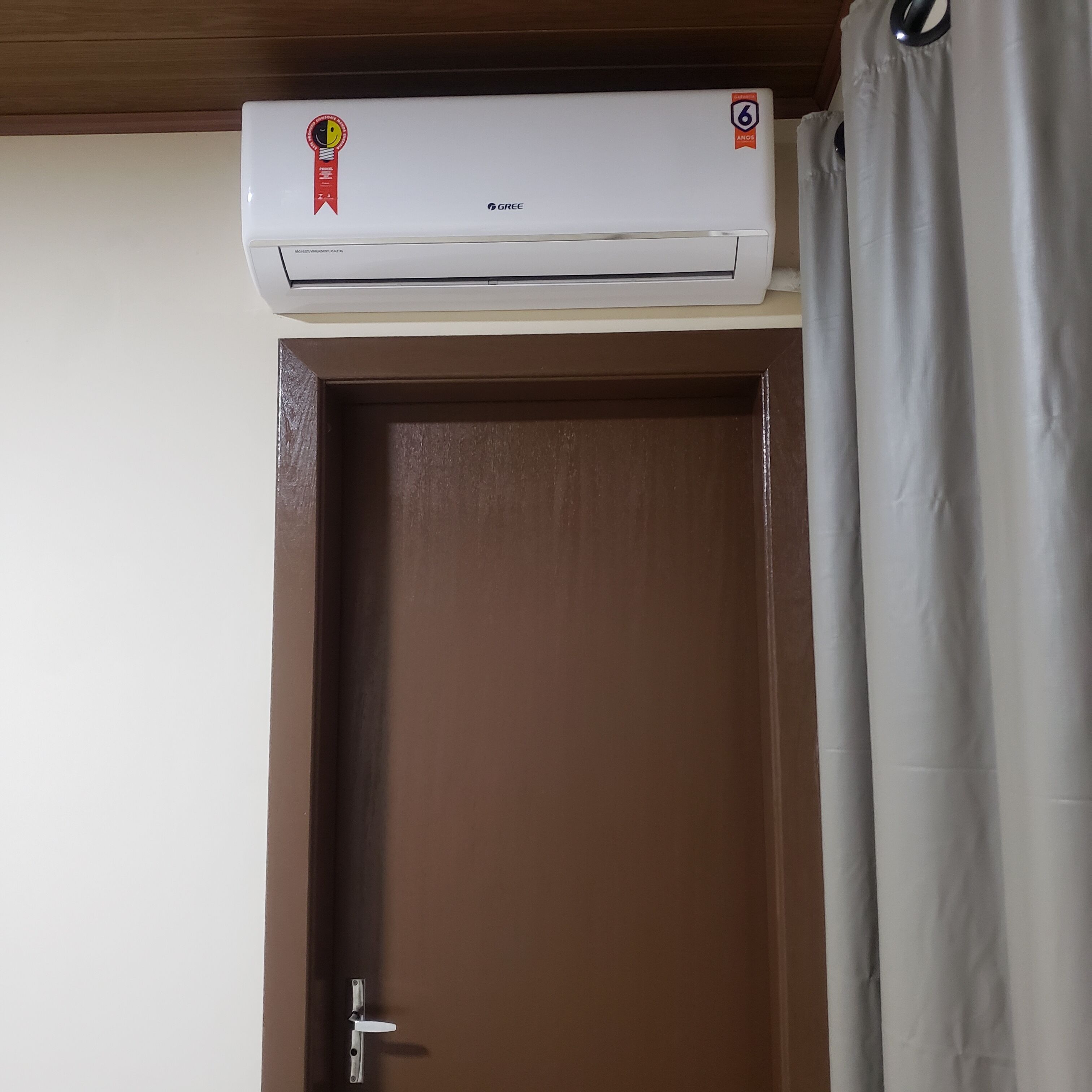 Un equipo de aire acondicionado montado sobre una puerta marrón cerrada con un picaporte metálico.