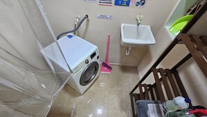 Un cuarto de lavandería con lavadora, un lavabo y una escoba.