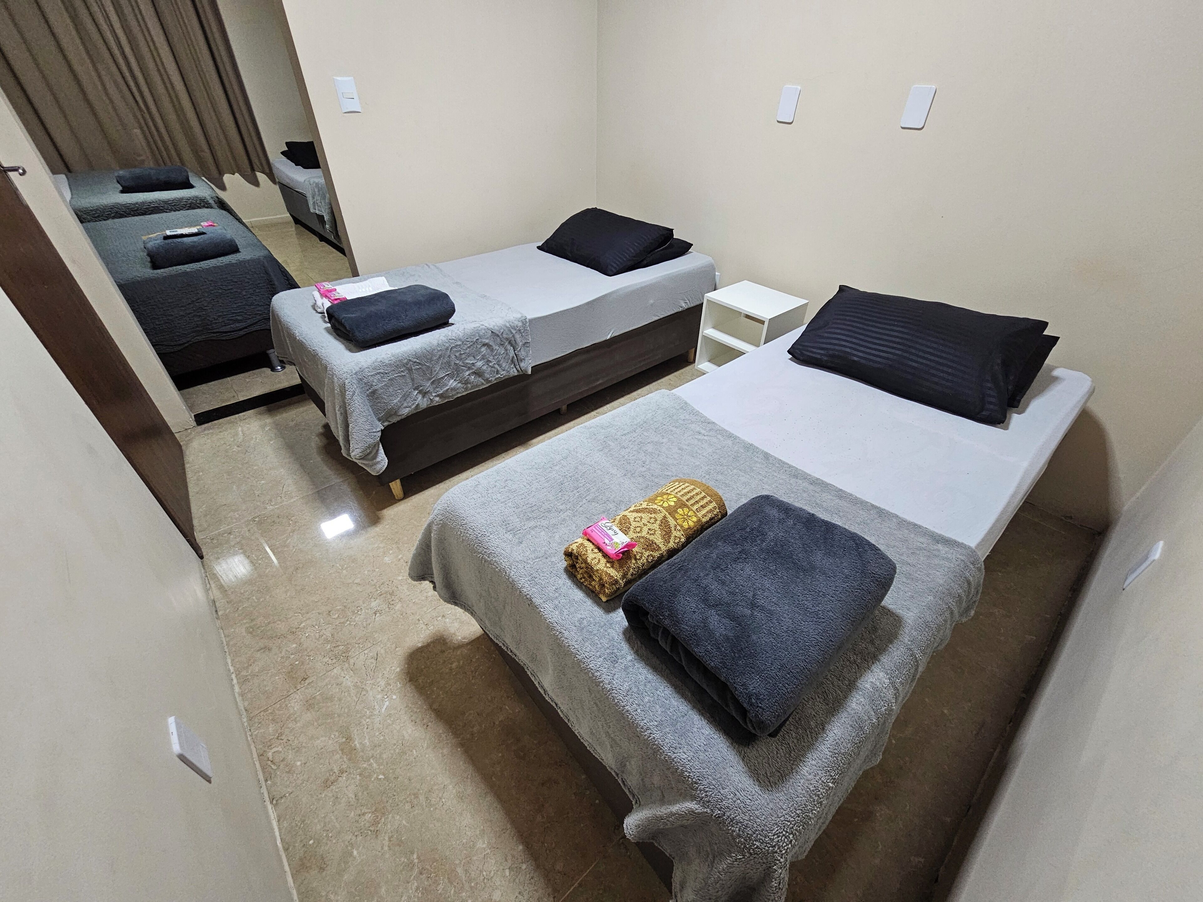 Habitación de hotel con dos camas, cada una con almohada y manta.