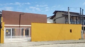 Un edificio con entrada protegida por un portón, una estructura amarilla a la derecha y un cielo despejado.