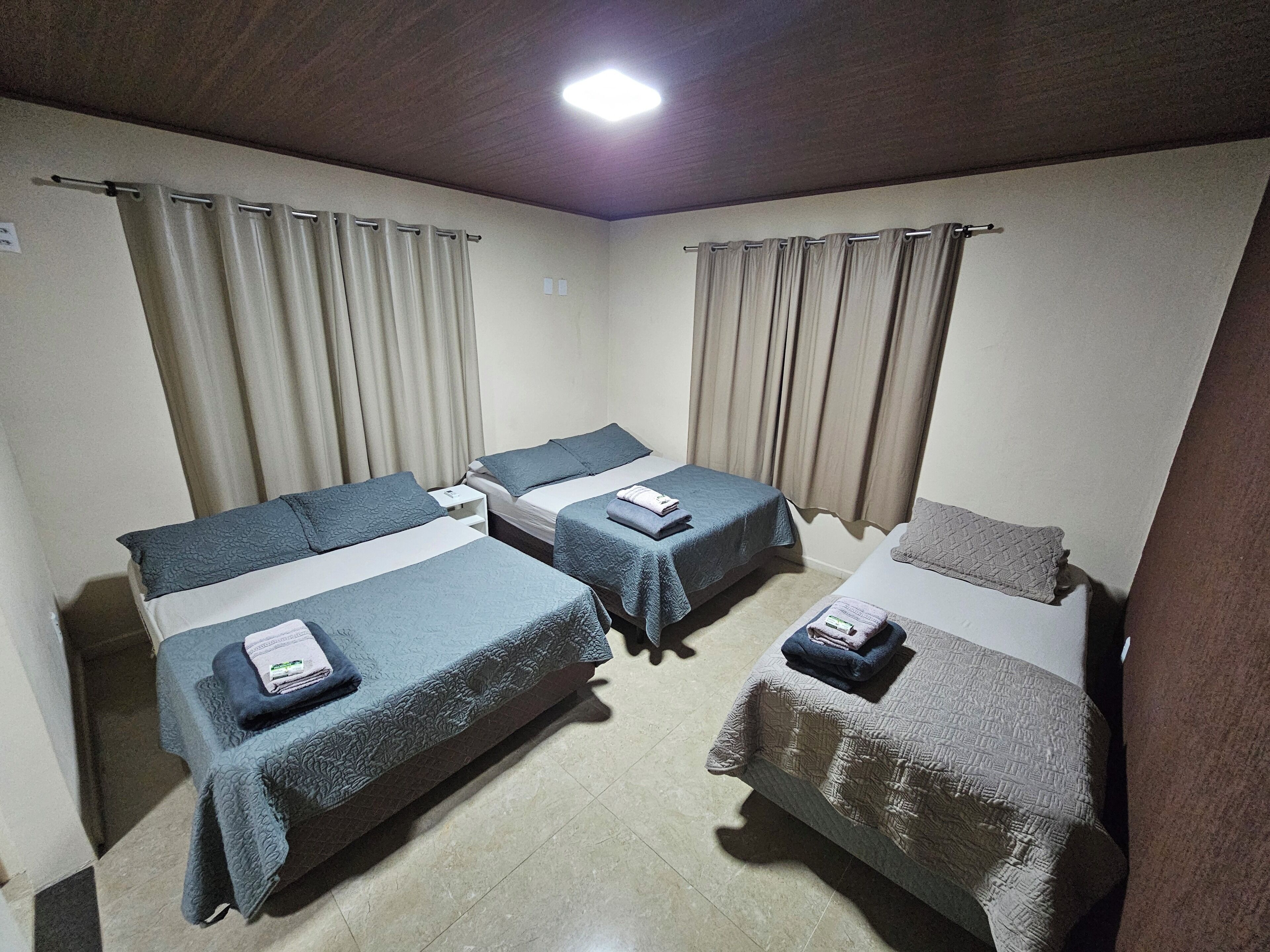 Une chambre d’hôtel avec deux lits simples, une petite table et un luminaire au plafond.