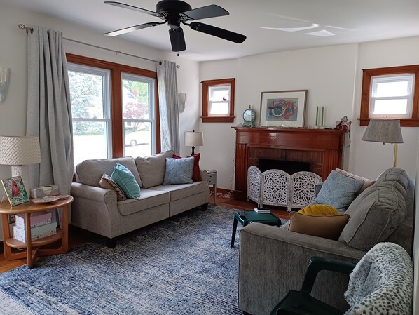 Una sala de estar con sofá, sillones, chimenea y ventilador de techo.