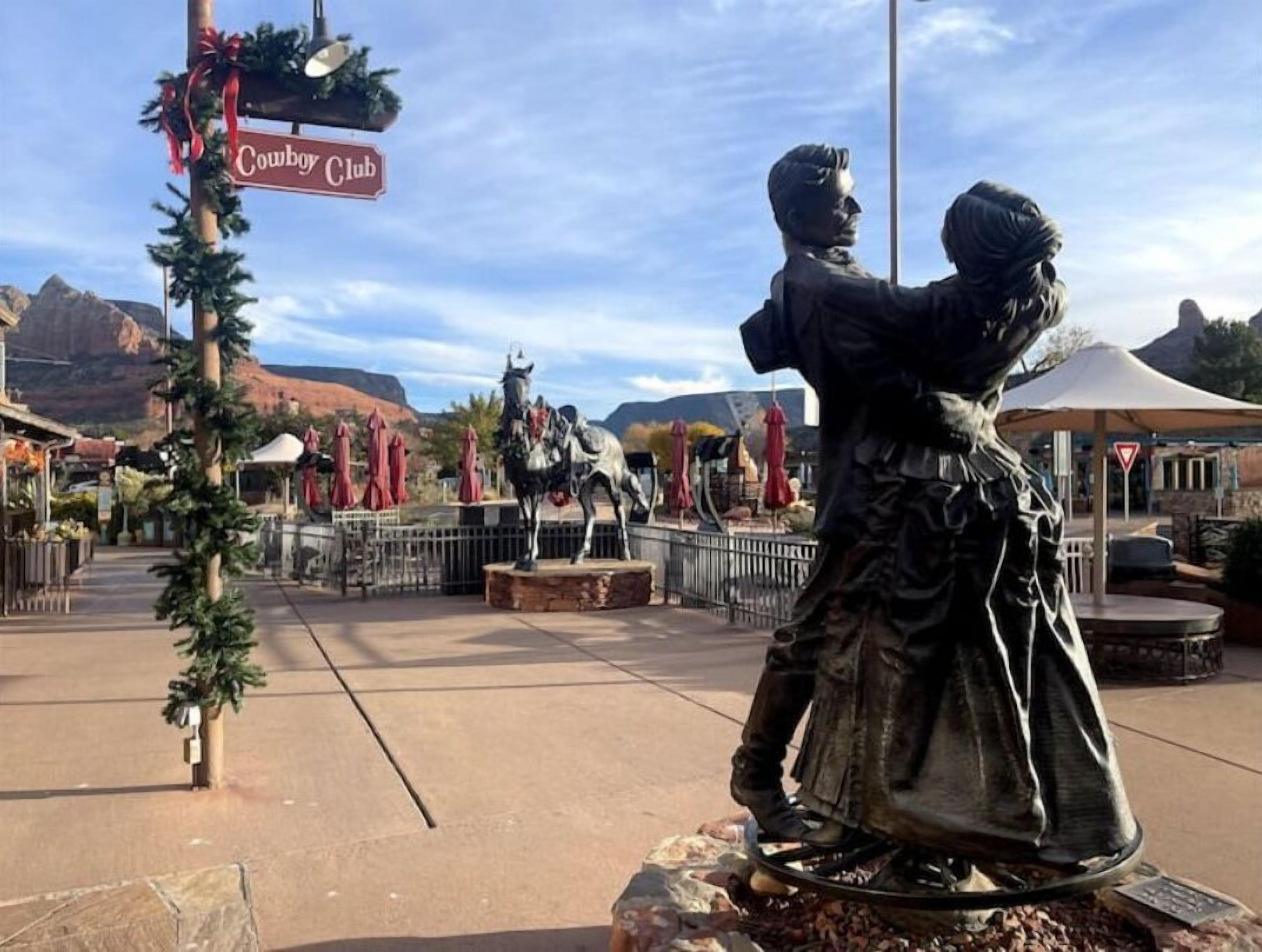 A statue of a cowboy and a woman in a Western setting with a sign reading "Cowboy Club".