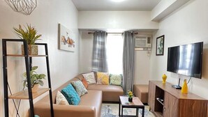 A modern living room with a sectional sofa, a coffee table, a TV, and a bookshelf. - Centrio Tower 926 (Cagayan de Oro)