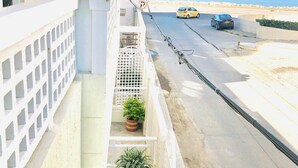 Un balcone con vasi di piante, vista sulla strada e cielo sereno.