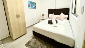 Una camera da letto con un letto, un armadio, un comodino, una lampada e una finestra.