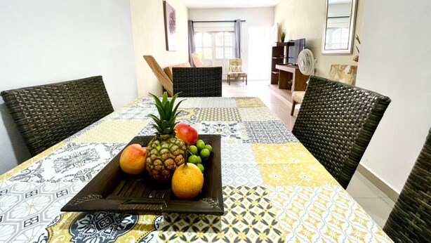 Zona pranzo con tavolo apparecchiato per due, con un elemento decorativo a base di frutta e tovaglia fantasia.