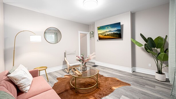 Ein modernes Wohnzimmer mit einem rosafarbenen Sofa, einem Glastisch, einem Spiegel, einer Lampe und einem Gemälde an der Wand.