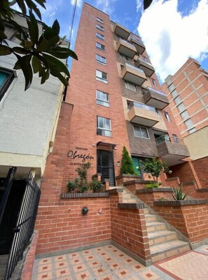 A multi-story building with a brick facade, a visible entrance, and a staircase leading to the entrance.