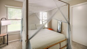 Una camera da letto con un letto a baldacchino, un comodino, una lampada e una finestra con tende.
