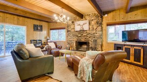 Una sala de estar acogedora con chimenea de piedra, sofás de cuero y un televisor.