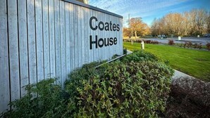 A sign reading "Coates House" on a building facade with a wooden panel design, surrounded by greenery and a clear sky. - Coates House one bed - Nailsea (Bristol)
