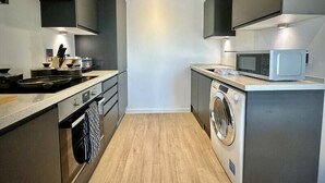 Cozinha compacta com micro-ondas, máquina de lavar e pia.