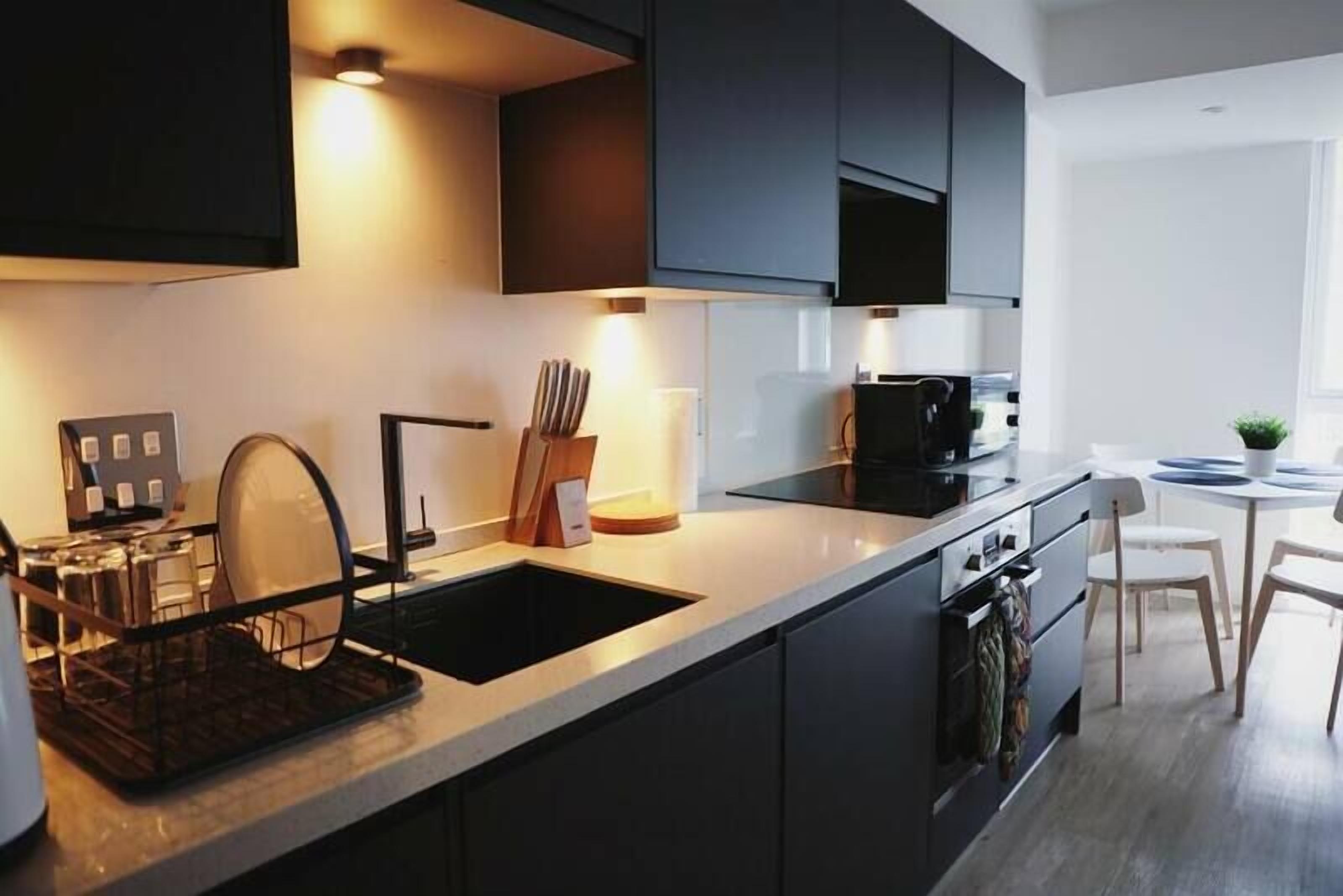 A modern kitchen with a built-in dishwasher, a sink, and a stove. There is a dining area with a table and chairs.
