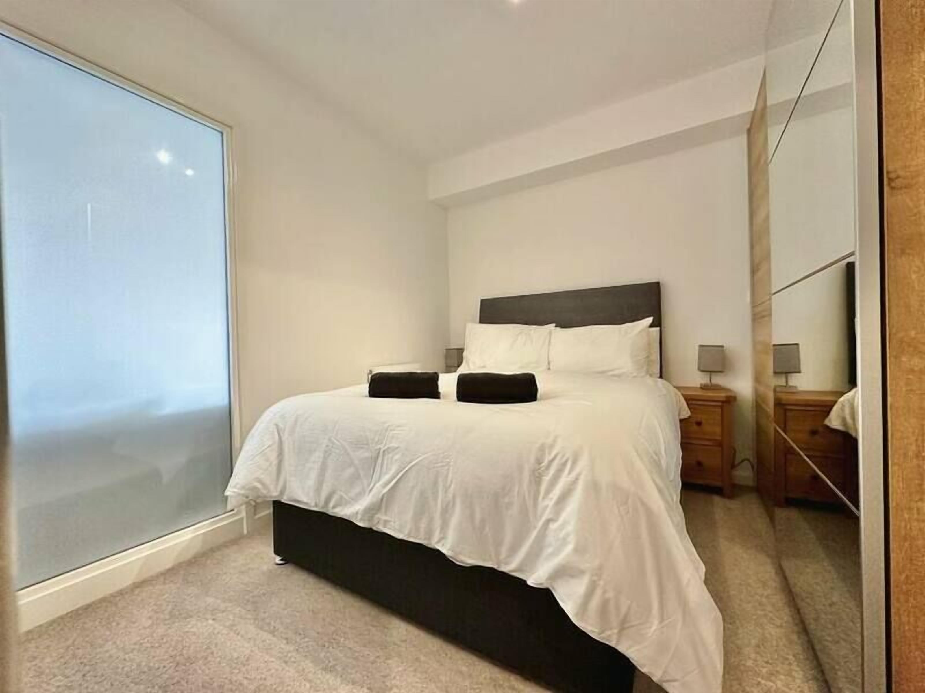 Et soveværelse med en stor seng, et natbord, et spejl og et vindue.