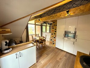 Una cucina compatta con mobili bianchi, un tavolo da pranzo in legno e un forno integrato.