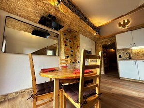 Un tavolo da pranzo in legno con sedie, una parete per l'arrampicata e un angolo cottura con mobili.