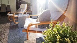 A modern living room with two wooden-framed chairs with white cushions, a grey rug, and a potted plant. - 2 bedroom nice home in Lemmer (Lemmer)