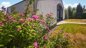A modern building with a large arched entrance, surrounded by lush greenery and pink flowering plants. - 2 bedroom nice home in Lemmer (Lemmer)