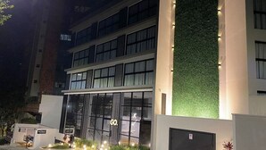 Un edificio moderno con fachada de vidrio, jardín vertical verde e iluminación de señalización.