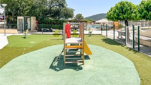 Ein Spielplatz mit Rutsche, Klettergerüst und Kunststoffrasen.