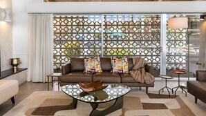 Un salon moderne avec une table basse en verre, un canapé en cuir et des rideaux à motifs.