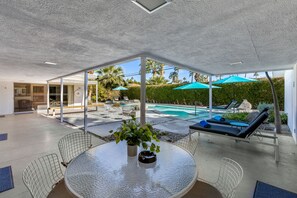 A modern outdoor patio with a glass enclosure, a pool, and lounge chairs. - Deepwell Mid-Century Classic (Palm Springs)