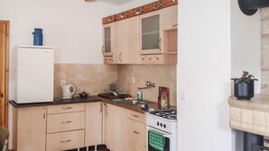 Een kleine keuken met een witte koelkast, een fornuis en houten kastjes.