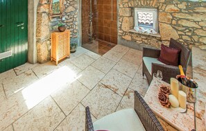 A stone-walled room with a shower, wicker furniture, and a table with bottles and glasses. - Pet friendly home in Moscenicka Draga with sauna (Moscenicka Draga)