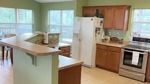 Une cuisine dotée d’un îlot central, de meubles de rangement en bois, d’un réfrigérateur et d’une cuisinière.