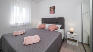 A bedroom with a large bed, a bedside table, a nightstand, a window with sheer curtains, and a painting on the wall. - 2 bedroom beautiful home in Zeliski (Zeliski)