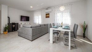 A modern living room with a grey sofa, a dining table with chairs, and a TV mounted on the wall. - 2 bedroom beautiful home in Zeliski (Zeliski)