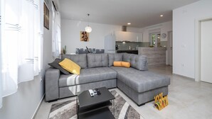A modern living room with a grey sectional sofa, a black coffee table, and a kitchen in the background. - 2 bedroom beautiful home in Zeliski (Zeliski)