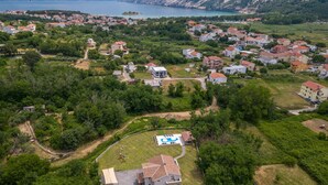 An aerial view of a residential area with houses, a swimming pool, and a large building with a red roof. - Pet friendly home in Lopar (Lopar)