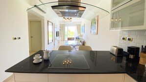 Una cocina moderna con una isla central, horno empotrado y extractor de humos con puerta de vidrio.