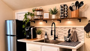 A kitchen with a stainless steel refrigerator, a coffee machine, a sink, and a potted plant. - Ouachita Spring Studio Stay- Sleeps 4 (Mena)
